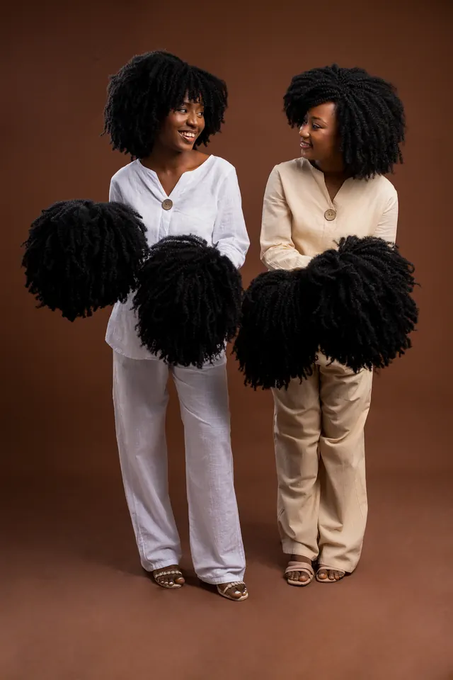 Keren e Clara, fundadoras da K.C Coroa Crespa, a segurar perucas afro feitas por elas